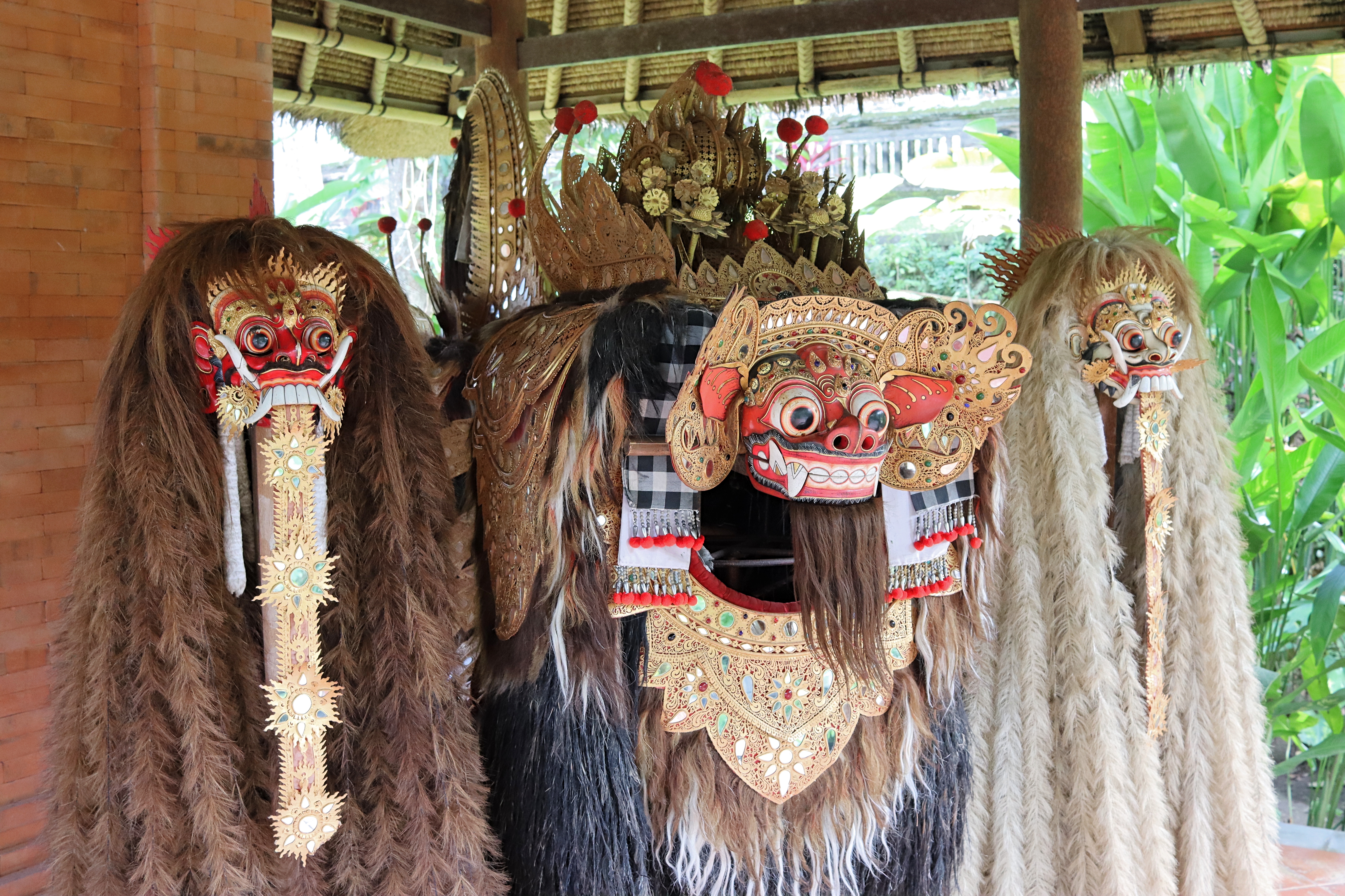 Traditional Balinese masks displayed in a cultural setting, featuring intricate designs and decorations, used in local performances.
